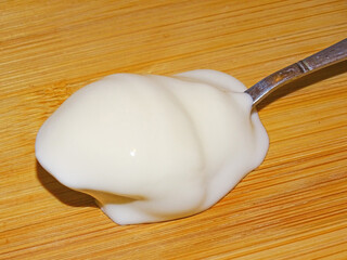 Yogurt on a spoon on a wooden background