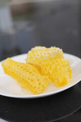 A close-up of a plate of fresh honeycomb against a background of vibrant sunflowers. Perfect for concepts of natural sweetness, sustainable living, beekeeping, and organic farming.