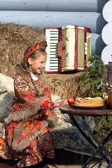 A blonde girl in a national Russian costume on the Maslenitsa holiday. A beautiful russian girl in a national costume made of a fur cape and kokoshnik on the background of a hayloft. 