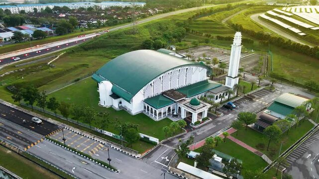 4K aerial view of Masjid Perodua, Bukit Beruntung, surrounded by housing, roads, and greenery, featuring a green roof and spacious parking.