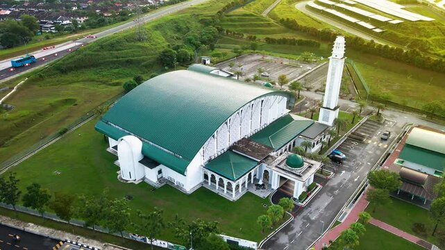 4K aerial view of Masjid Perodua, Bukit Beruntung, surrounded by housing, roads, and greenery, featuring a green roof and spacious parking.