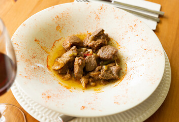 Delicious lamb stew with garlic shoots seasoned with smoked paprika on white plate. Traditional Spanish cuisine