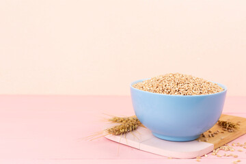 Bowl with spelt grain and ears on wooden table