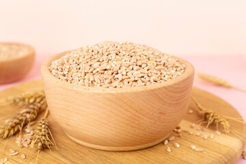 Bowl with spelt grain and ears on wooden table