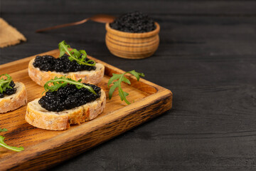 Bread slice with black caviar served on on wooden table