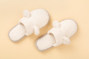 Soft teddy slippers on color background, top view