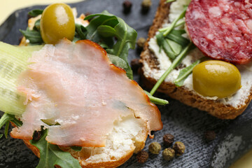 Board with delicious sandwiches and peppercorns, closeup