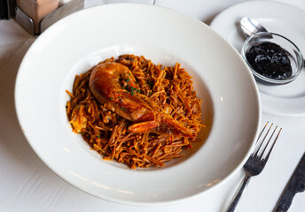 Delicious traditional Valencian seafood fideua, savory noodle dish with shrimps and clams served with black garlic aioli.