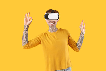 Naklejka premium Happy young man in VR headset on yellow background