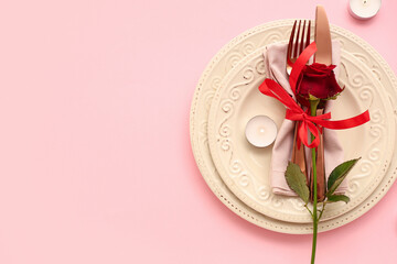 Beautiful table setting with red rose and burning candles on pink background. Valentine's Day celebration
