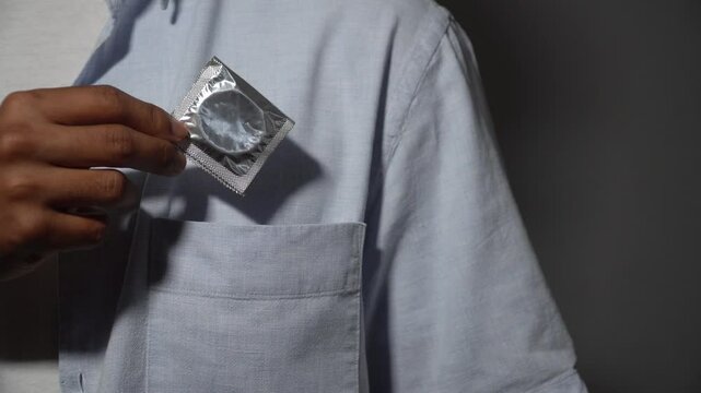 Man putting condom in shirt pocket