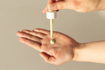 Closeup of a person applying green serum for redness.