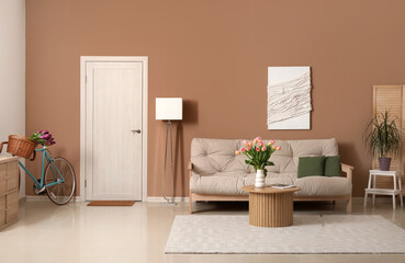 Interior of beautiful living room with beige sofa, table and vase with tulips
