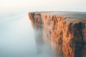 A dramatic clifftop shrouded in mist, bathed in the warm glow of sunrise or sunset.