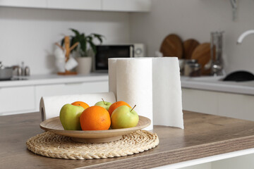 Rolls of paper towels with fruits on table in kitchen, closeup