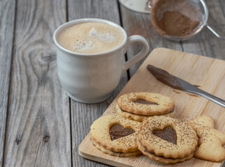 Still life of homemade heart-shaped cookies along with a coffee and kitchen utensils. Romantic snack