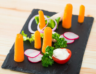 Close up of tasty dish of fresh vegetables and carrot dominant served at plate