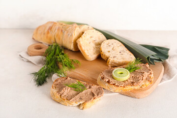 Wooden board with toasts, tasty pate, dill and green onion on light background
