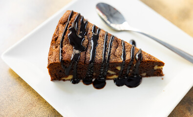 Slice of traditional pie brownie with walnuts and chocolate icing. Delicious chocolate pastries..