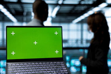 Focus on green screen laptop used by computer scientists in data center inspecting servers,...