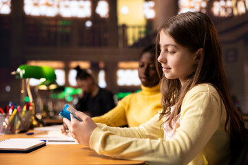 Teenagers immersed in reading literary works from the school library database, focusing on their education and preparing for mandatory assignments or lectures. Diverse girls love to read.