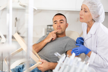 Female cosmetologist confidently presents cosmetic procedure's results to male client using mirror.