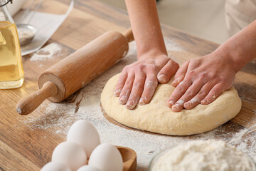 Woman kneading fresh dough in kitchen