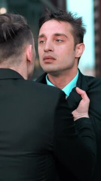 Angry Young businessman grabbing his colleague by the lapels of suite. He want to start fighting. Hard conversation and debate. Boss work with smartphone and dismiss his subordinate. Glass business