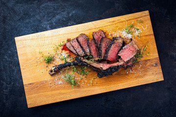 Traditional grilled barbecue dry aged tomahawk beef steak meat with salt and fresh herbs served and...