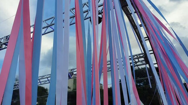 Ribbons with the transgender pride flag waving in the wind, horizontal footage.