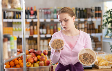 Female shopper chooses yakisoba - Japanese cuisine dish, while shopping in a supermarket