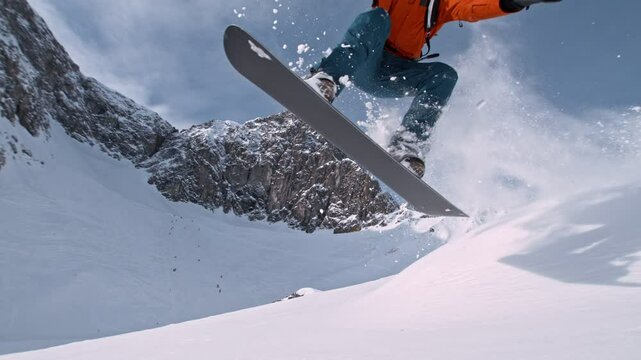 Off Piste Snowboarder Jumping. Super Slow Motion, 1000 fps. Snowboarding on Free Ride off Piste Slope on Sunny Day With Clear Blue Sky in European Alps Mountains, Austria.