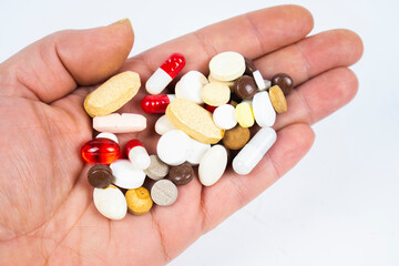Different pills in the palm of the hand, on a white background. View from above.