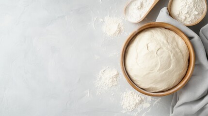 Fresh risen dough in a wooden bowl, surrounded by flour, ready for baking on a textured surface.
