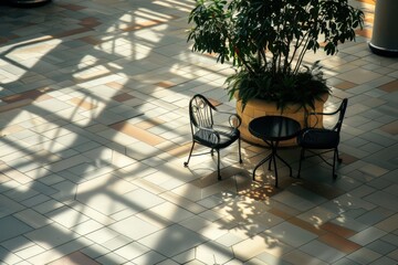 Obraz premium seating area in a shopping mall with two black chairs, a round table, and a large potted plant