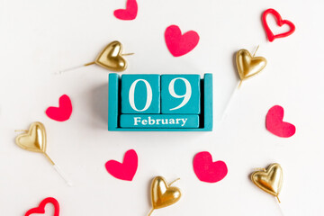 February 9. Blue cube calendar with month and date and decorative hearts on white background.