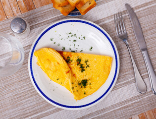 Delicious omelet from eggs on white plate in cafe