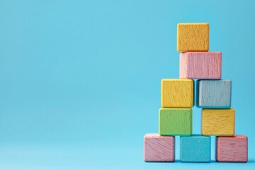 Colorful wooden building blocks stacked on a blue background, symbolizing creativity, play, and childhood development with pastel colors and a playful concept
