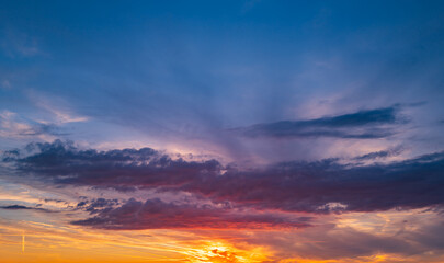 Sunset background. Dramatic majestic scenery sunset. Sky with clouds in sunset sky light background. Sunrise with clouds in various shapes. Calm sunset sky and sun through clouds over.