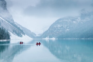 Snowy winter day, kayakers on a serene lake, surrounded by majestic mountains. Lake Louise, Banff National Park, Alberta, Canada © Zenstratus