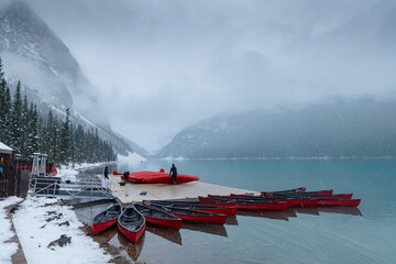 Snowy, misty day at Lake Louise. Staff prepare red canoes for winter.  Banff National Park, Alberta, Canada