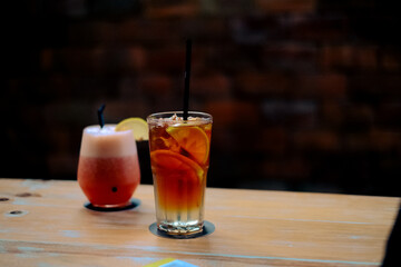 A glass of smoothies and a glass of refreshing and healthy ice lemon tea are served on the table.