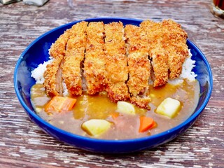 This photo showcases a delicious plate of chicken katsu curry served on a blue dish. The crispy, golden-brown fried chicken fillets are perfectly paired with a rich and savory curry sauce