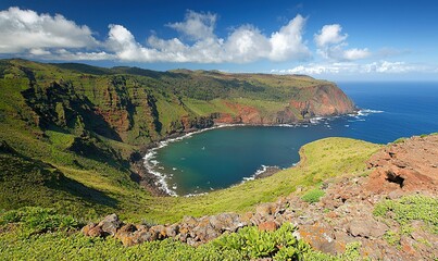Aerial view of a secluded bay with colorful cliffs, green hills, and blue ocean under a bright sky