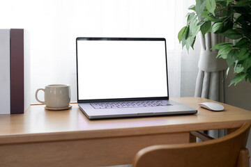 Laptop with blank white screen on wooden desk, home office, work from home.
