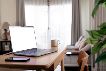 Laptop with blank white screen on wooden desk, home office, work from home.