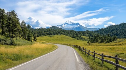 Naklejka premium Scenic Mountain Road with Lush Green Fields and Snow-Capped Peaks Under a Bright Blue Sky in a Peaceful Landscape Perfect for Nature Lovers and Adventure Seekers