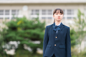学校の校舎の前に立つ制服姿の中学生・高校生・小学生
