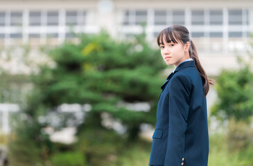 学校の校舎の前に立つ制服姿の中学生・高校生・小学生
