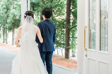 Fototapeta premium 結婚式場を歩く新郎新婦の後ろ姿（入場・結婚式・アジア人） 
